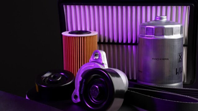 Auto parts car on black background with purple backlight. Fuel, oil, air filters and tension and idler rollers, poly V-belt rotate on turntable around its axis. Auto parts store and service station