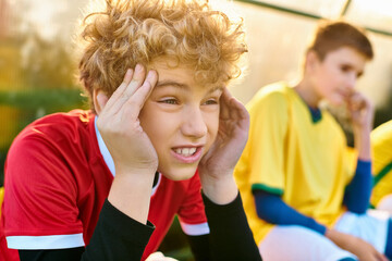 A young boy and another young man sitting side by side, engaged in conversation. Both individuals...