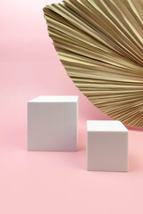 White square podium, dried palm leaf on pink background. Geometric abstract shapes for cosmetic product presentation. Two different sizes square shapes. Copy space.