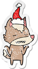 hand drawn distressed sticker cartoon of a wolf showing teeth wearing santa hat