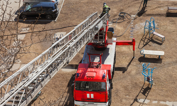 Top view of firefighter descending retractable ladder after extinguishing fire inside residential building in spring day