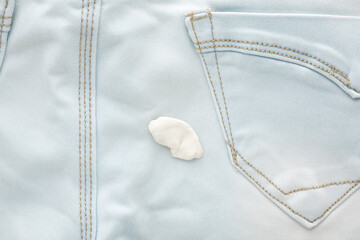 White chewing gum on light blue female jeans trousers. Closeup. Top down view.