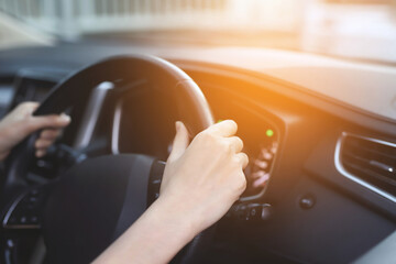 Close up of hands hold steering wheel young woman driving a car riding on the road. driver trip of...