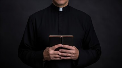Catholic priest in black robe holds Holy Bible standing in old church closeup. Senior pastor with book prepares for service in wooden building. Man of God prays during ceremony in country church - obrazy, fototapety, plakaty