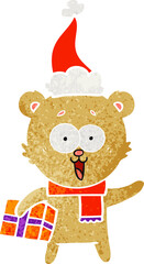 laughing teddy  bear with christmas present wearing santa hat