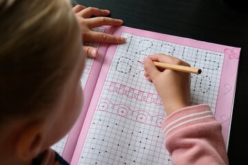 A preschool child learns to write in a workbook at home. The concept of home schooling 
