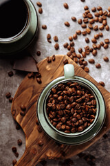 a cup of coffee on a dark background surrounded by coffee beans,