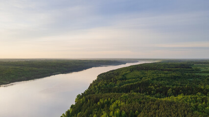 Aerial view of the Volga River, flowing surrounded by a spring green forest and colorful sunrise 