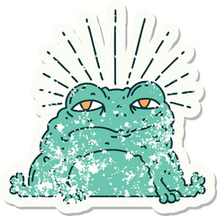 worn old sticker of a tattoo style toad character