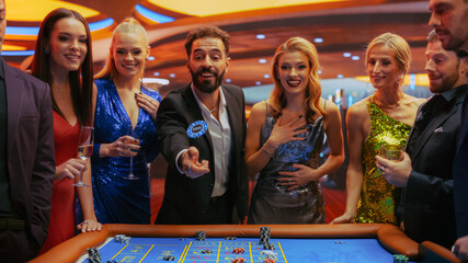 Cheerful Group of Rich Young People Gathered Around a Roulette Table at a Modern Casino. Handsome...
