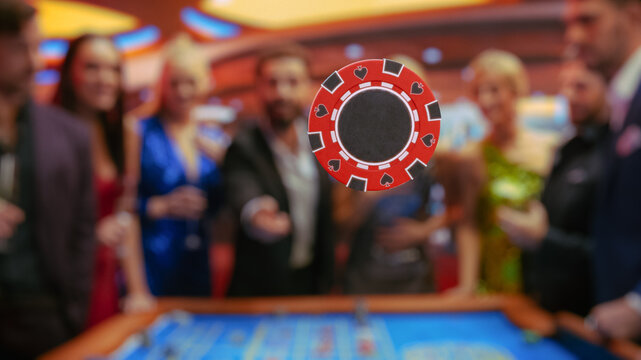 Multiethnic Young Adults Playing an Engaging Game of Roulette, Spending a Fun Evening in a Luxurious Hotel Casino. Enthusiastic Gambler Tossing a Red Casino Chip with Template Placeholder