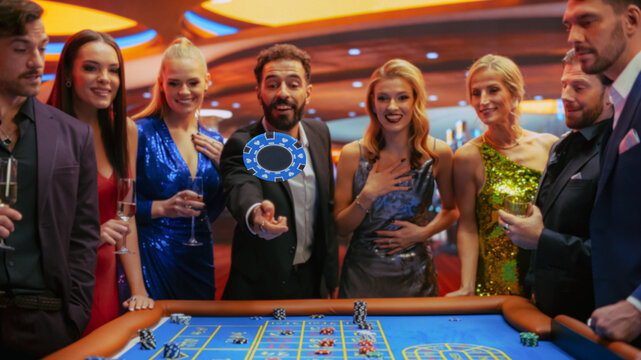 Successful Men and Women Partying in Luxurious Casino. Young People Gambling at a Roulette Table, Putting High Stakes Bets. Man Tossing a Blue Chip with a Placeholder, Crowd Cheering, Enjoying Drinks