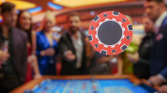 Multiethnic Young Adults Playing an Engaging Game of Roulette, Spending a Fun Evening in a Luxurious Hotel Casino. Enthusiastic Male Gambler Tossing a Red Casino Chip with Template Placeholder