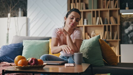 Tired woman drinking coffee after remote laptop work late evening. Girl relaxing