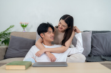 Young Asian couple share a tender moment. a man leaning on a woman's lap. The couple was smiling and relaxing at home.