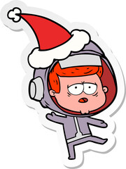 hand drawn sticker cartoon of a tired astronaut wearing santa hat