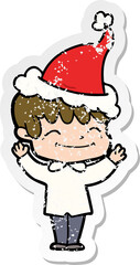 hand drawn distressed sticker cartoon of a happy boy wearing santa hat