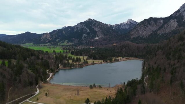 View of castle Neuschwanstein from alpine lake Schwansee In spring. Schwansee im Ostallgau in Bayern sudostlich von Fussen im Gemeindegebiet von Schwangau. Schloss Neuschwanstein und der See. 