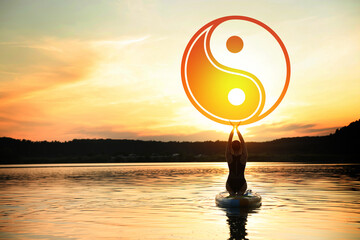 Woman meditating on SUP board on river at sunset, back view. Yin and yang symbol