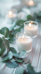 Obraz na płótnie Canvas A delicate arrangement of white candles and eucalyptus leaves on a striped wooden table, highlighted by the soft glow of candlelight and a serene bokeh background.
