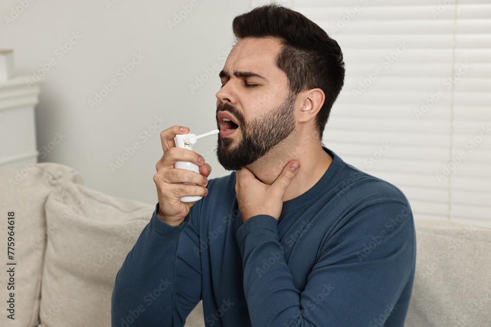 Sticker Young man using throat spray at home