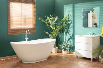 Modern bright bathroom with green walls, wooden floor, plant and window. High quality photo
