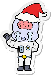 hand drawn sticker cartoon of a big brain alien crying wearing santa hat