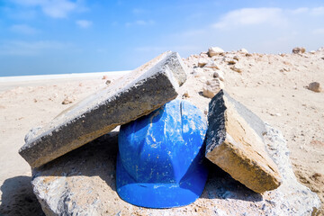 Hastily abandoned construction helmet in sand. Helmet is able to withstand impact of a concrete...