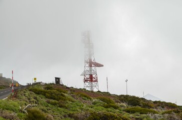 Fototapeta na wymiar Transmission tower covered in fog on a cloudy day on the hillside