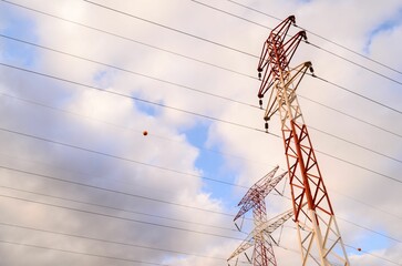 Low angle shot of high voltage electric transmission towers under a cloudy sky