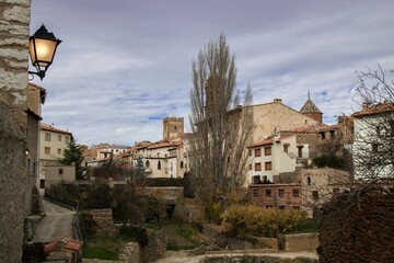 Town with buildings surrounded by trees and a street light on a building wall on a gloomy day