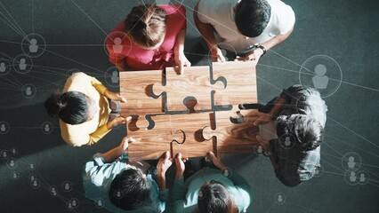 Top down view of business people gathering jigsaw together at meeting. Aerial view of diverse team collect or put piece of jigsaw puzzle together with computing global networking community. Symposium.