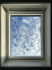 View of the blue sky with windy clouds through white aluminium window on a sunny day