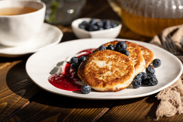 Breakfast with cheesecakes, pancakes with sour cream, mashed berries and fresh blueberries