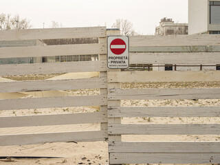 Segnale di proprietà privata con divieto di accesso su una recinzione di legno in una spiaggia.