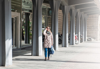 Beautiful stylish woman with bag and sunglasses standing near building on the street of Belgrade, Serbia
