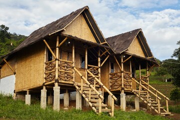 Low-angle view of two split houses made of bamboo in the mountains