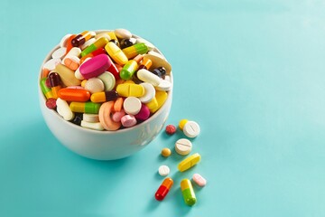 Closeup shot of various kinds of colorful medicines filling a bowl unitl they overflowed and fell