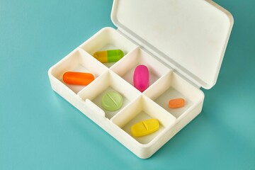 Closeup shot of six different coloured medicine pieces in a daily pills medicine box