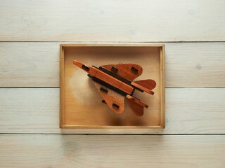 Wooden toy jet plane in a wooden box on a wooden background