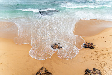 A high-angle shot of rocks and waves on Rio Vermelho beach in Salvador, Bahia, Brazil.