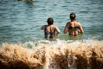 Mother and daughter entering the water at Porto da Barra beach. Salvador, Brazil.