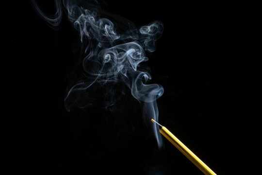 Closeup of colorful pencil and white smoke on a black background