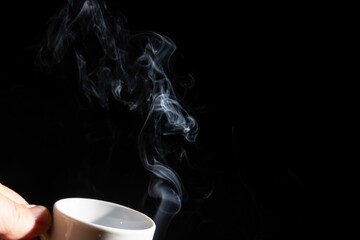 Hand holding a white cup with smoke against a black background