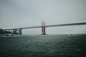 Distant shot of the Golden Gate Bridge in Baker Bridge covered in fog in gloomy weather