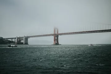Glasschilderij Baker Beach, San Francisco Distant shot of the Golden Gate Bridge in Baker Bridge covered in fog in gloomy weather