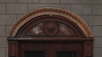 Closeup shot of brown door with white graffiti tags
