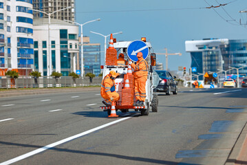 Minsk, Belarus. Apr 1, 2024. Workers in orange uniform on paint striping truck installing orange...