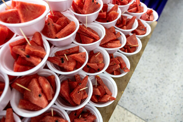 Red watermelon, cut into pieces and inserted with toothpicks. - obrazy, fototapety, plakaty