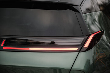 Right rear light shining on new modern electric sedan car. Right turn indicator signal. Red tail lights closeup. Modern concept supercar exterior design detail, headlight. Back view. Concept of future - obrazy, fototapety, plakaty